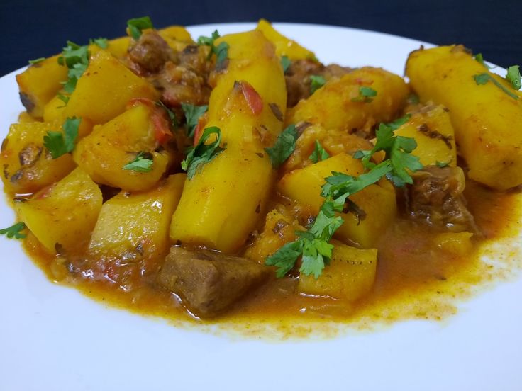 a white plate topped with potatoes and meat