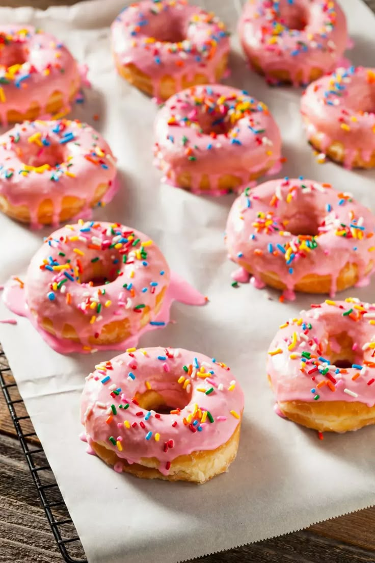 pink frosted doughnuts with sprinkles on a white paper towel