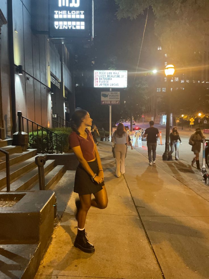 a woman is standing on the sidewalk talking on her cell phone while others walk by