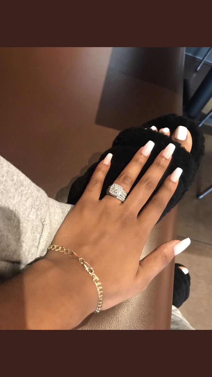 a woman's hand with white nails and a diamond ring on her left wrist