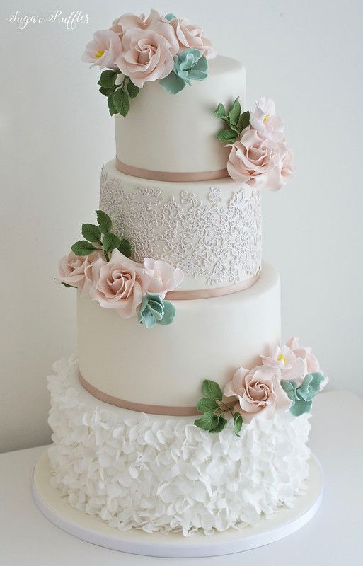 a three tiered white wedding cake with pink flowers on the top and bottom layer