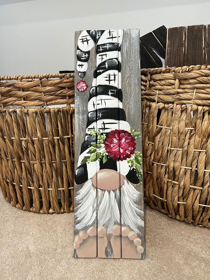 a wooden sign with flowers painted on it in front of wicker baskets and woven baskets