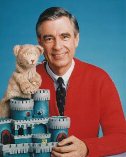 a man in a red sweater holding a teddy bear next to a castle with a cat on top