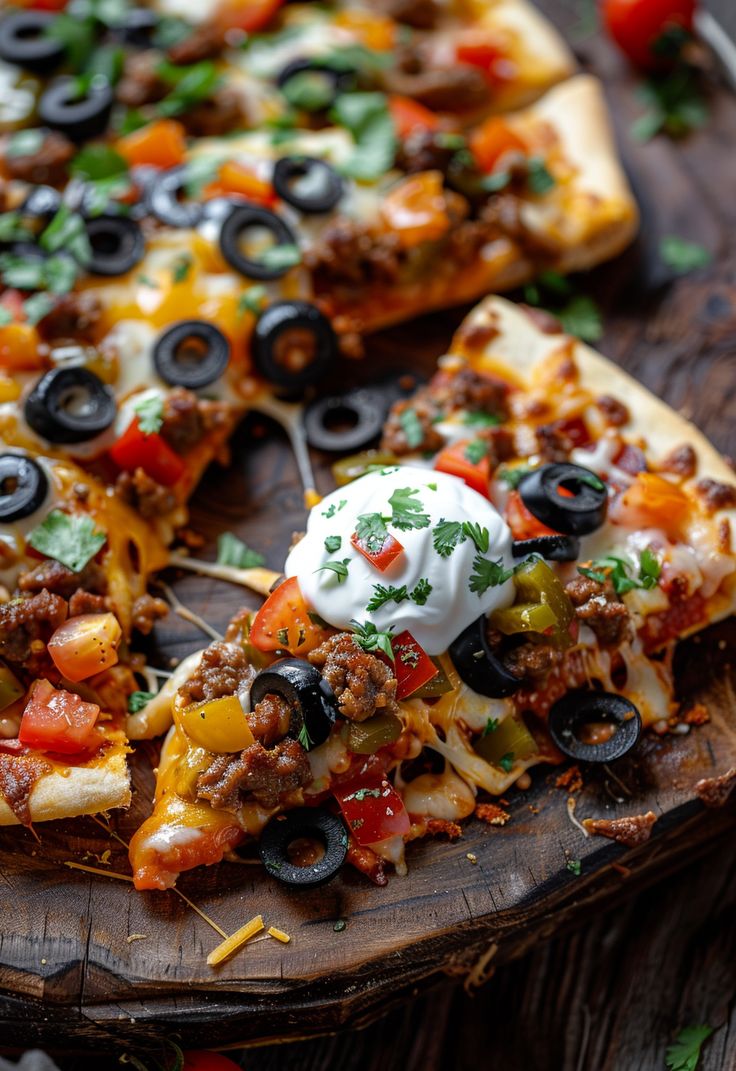 a pizza with olives, cheese and other toppings on a wooden platter