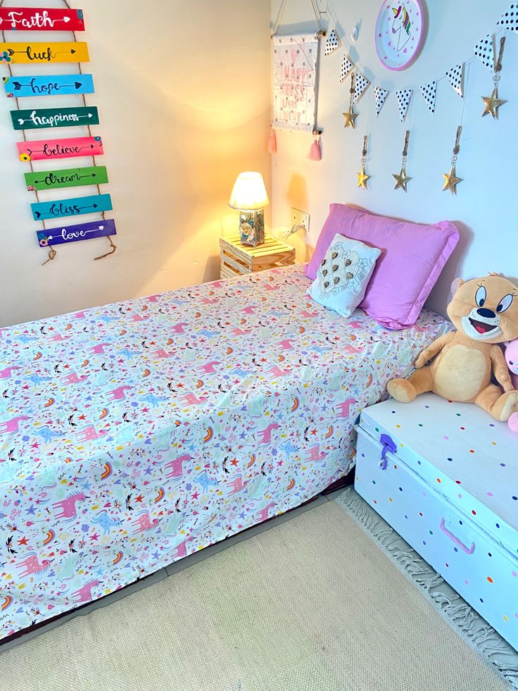 a bed with a teddy bear sitting on top of it next to a night stand