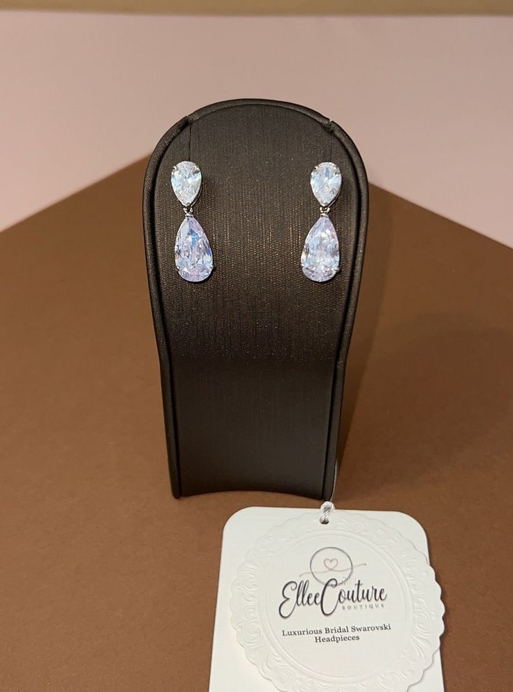 a pair of earrings sitting on top of a wooden table next to a card holder