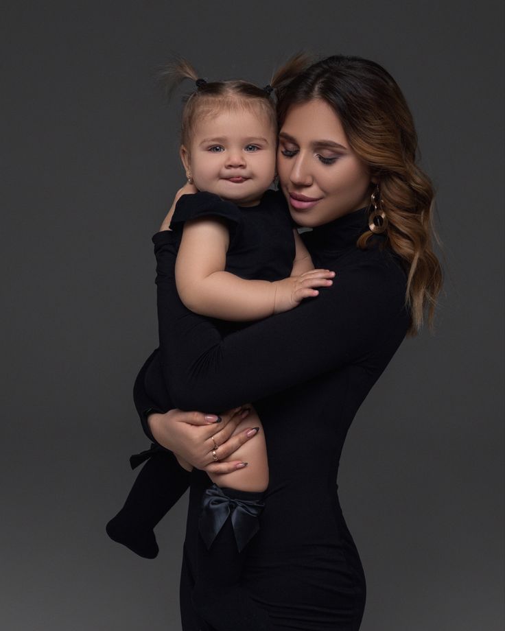 a woman holding a small child in her arms and looking at the camera with an intense look on her face