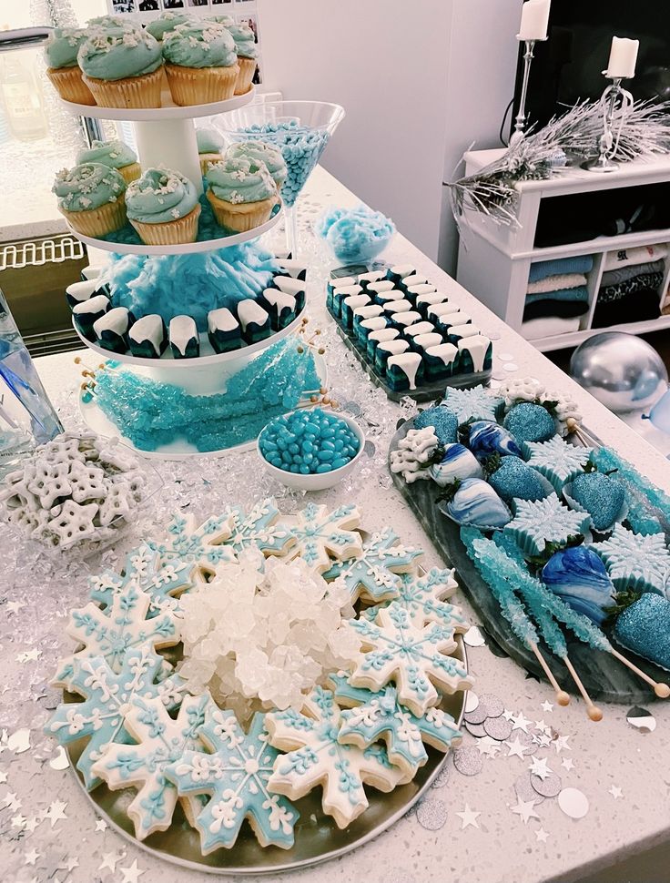 a table topped with lots of blue and white desserts next to cupcakes