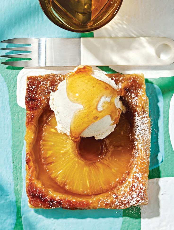 a piece of fruit is sitting on a plate next to a fork and glass with ice cream