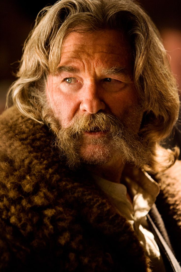 an older man with long hair and a beard wearing a fur coat looking at the camera