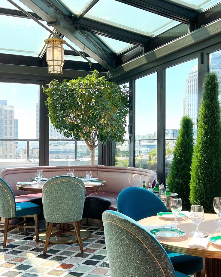 a dining room with tables and chairs in front of large windows overlooking a cityscape