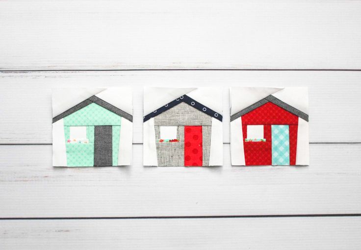 three small houses made out of fabric sitting on top of a wooden table