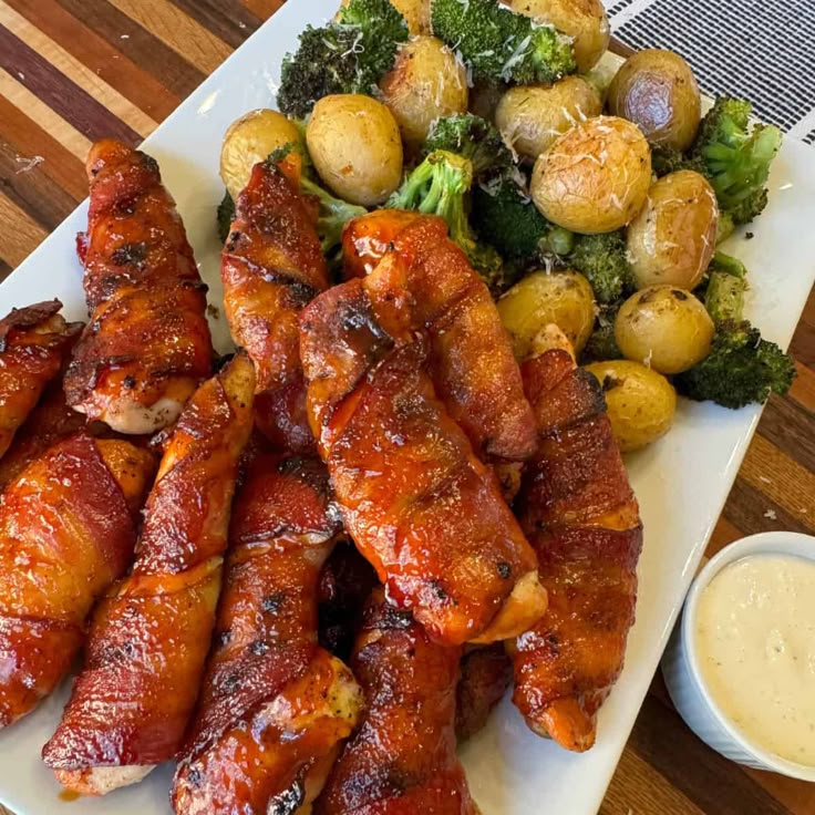 a plate full of chicken wings, potatoes and broccoli with dipping sauce on the side