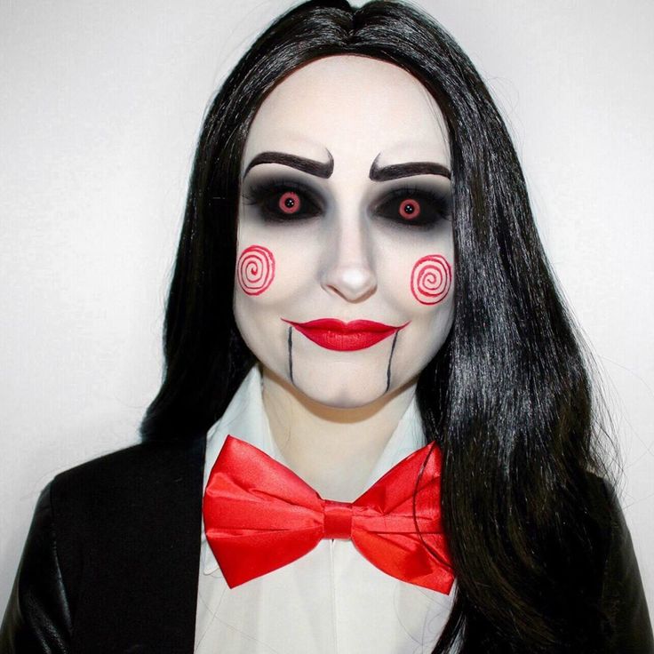 a woman with black hair and makeup wearing a red bow tie, white face paint and long black hair