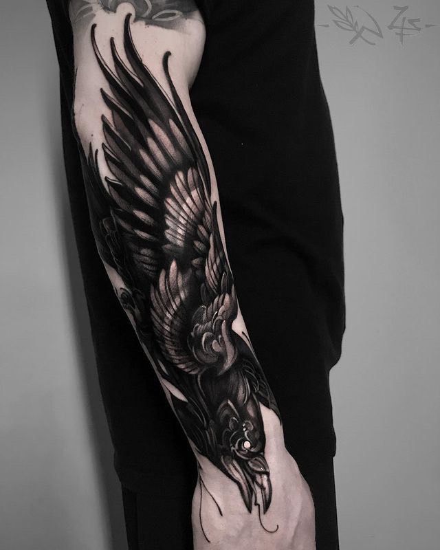 a man's arm with a black and white tattoo design on it, featuring an eagle