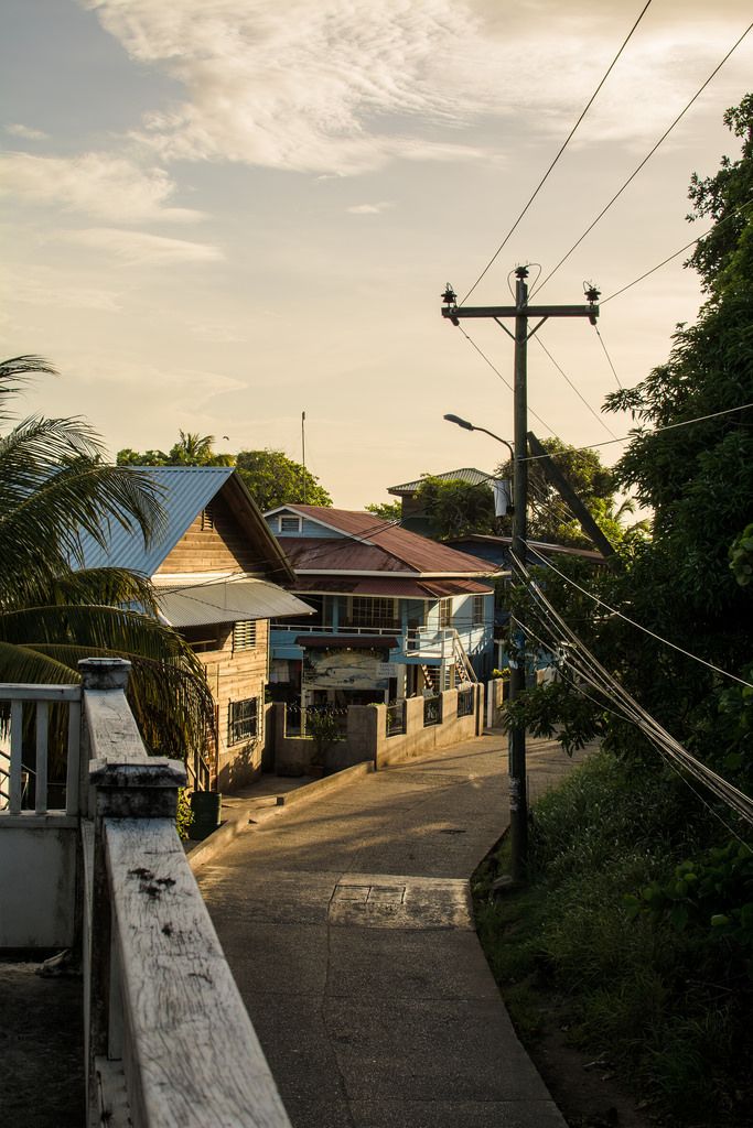 an empty street with power lines above it and houses in the distance on either side