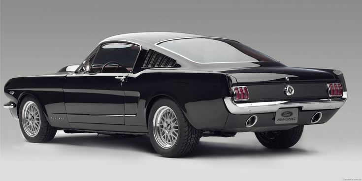 an old black mustang car with a white top and chrome rims is shown in front of a gray background