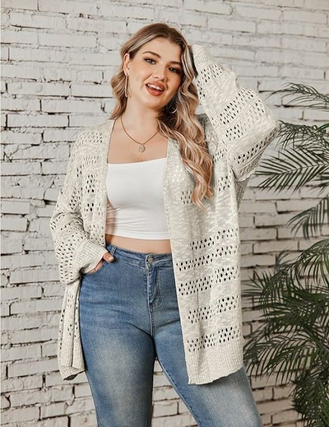 a woman posing in front of a brick wall with her arms behind her head, wearing jeans and a white top