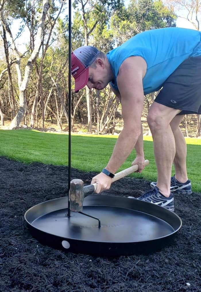 a man bending over to pick up something from a pan on top of the ground