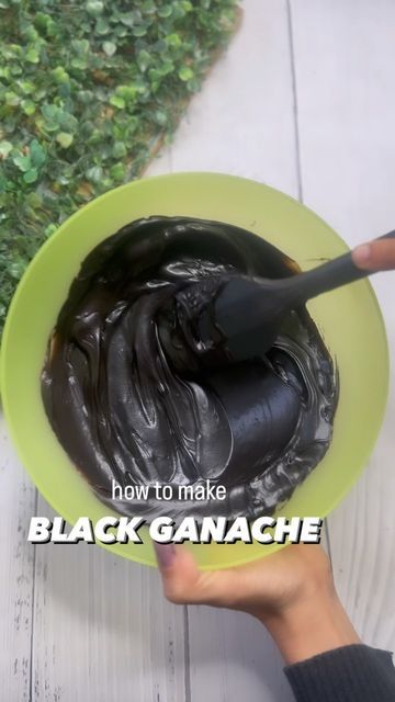 a person holding a green bowl filled with black ganache