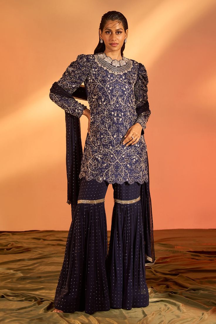 Navy blue kurta with floral hand embroidery. Comes with sharara and a dupatta.
Components: 3
Pattern: Hand embroidered
Type Of Work: Floral
Neckline: Round
Sleeve Type: Full
Fabric: Silk, Georgette, Lining : Shantoon
Color: Blue
Other Details: 
Side slits on kurta
Occasion: Mehendi and Haldi, Sangeet - Aza Fashions Blue Fitted Sharara With Intricate Embroidery, Blue Chinon Kurta With Intricate Embroidery, Fitted Blue Palazzo Set With Intricate Embroidery, Blue Fitted Palazzo Set With Intricate Embroidery, Royal Blue Sharara With Intricate Embroidery For Festive Occasions, Blue Chinon Kurta With Long Sleeves, Festive Blue Sharara With Intricate Embroidery, Blue Chinon Long Sleeve Kurta, Anarkali Sharara With Intricate Embroidery In Royal Blue