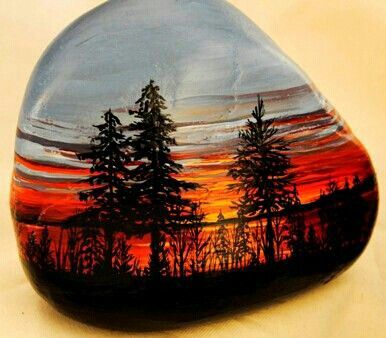 a painted rock sitting on top of a white table next to a tree filled forest