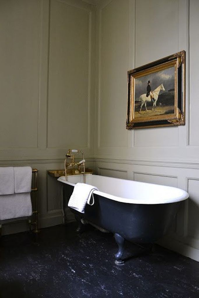 an old fashioned bathtub in the middle of a bathroom with white walls and black flooring