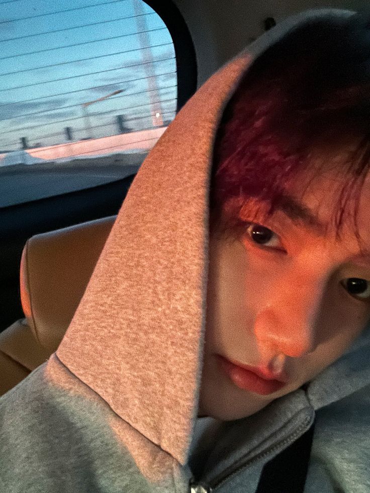 a young man with red hair wearing a grey hoodie and looking at the camera