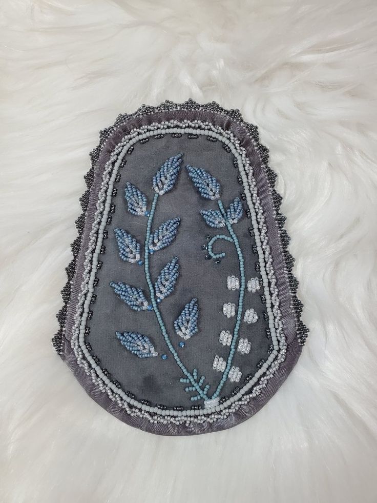 an embroidered patch with blue flowers and leaves is on a white furnishing area