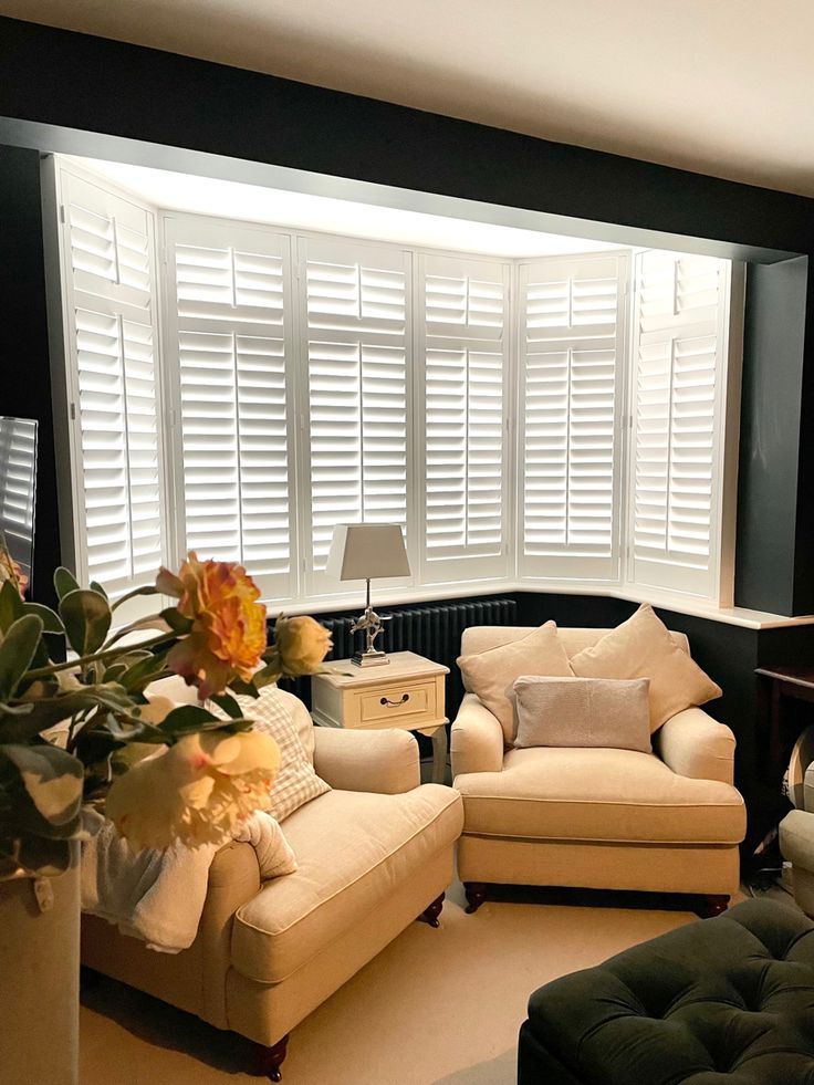 a living room filled with furniture and flowers on top of the couches in front of large windows