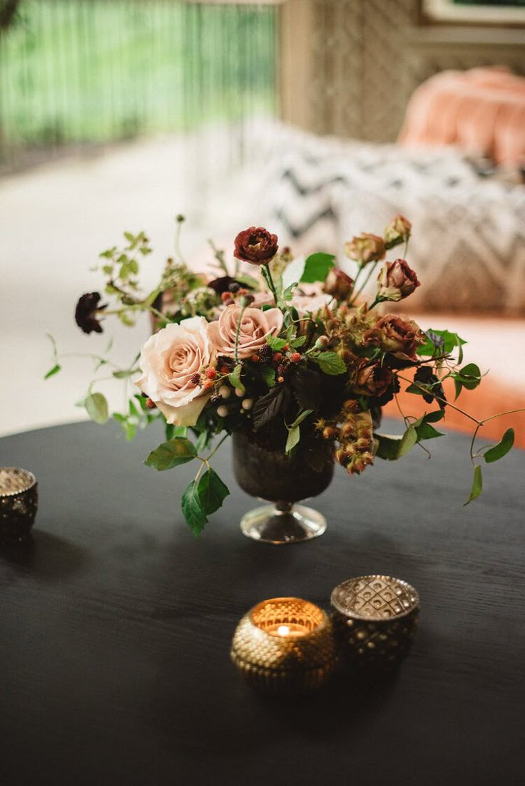 a vase filled with flowers sitting on top of a black table next to two candles