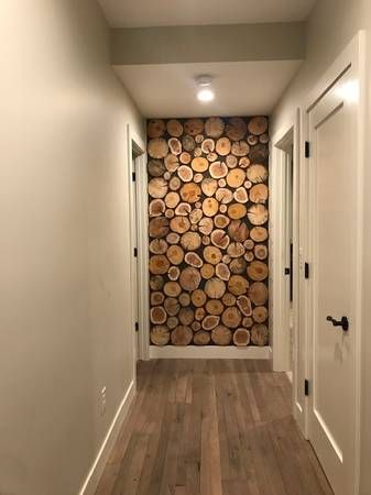 a long hallway with wood logs on the wall and hardwood flooring in front of it