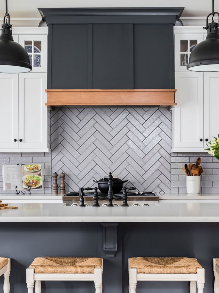 a kitchen with white cabinets and gray backsplash, two pendant lights over the stove