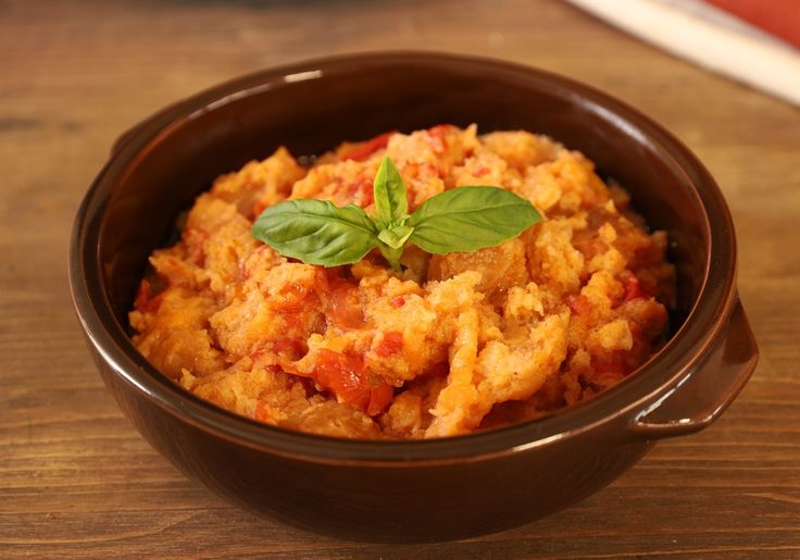 a brown bowl filled with food on top of a wooden table