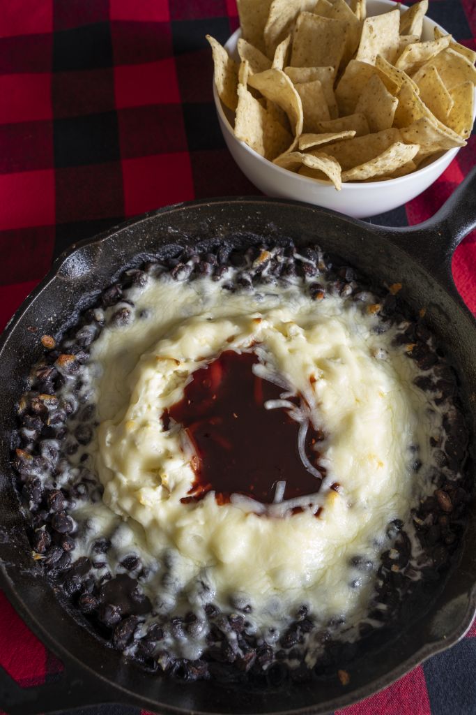 a skillet filled with mashed potatoes next to a bowl of tortilla chips