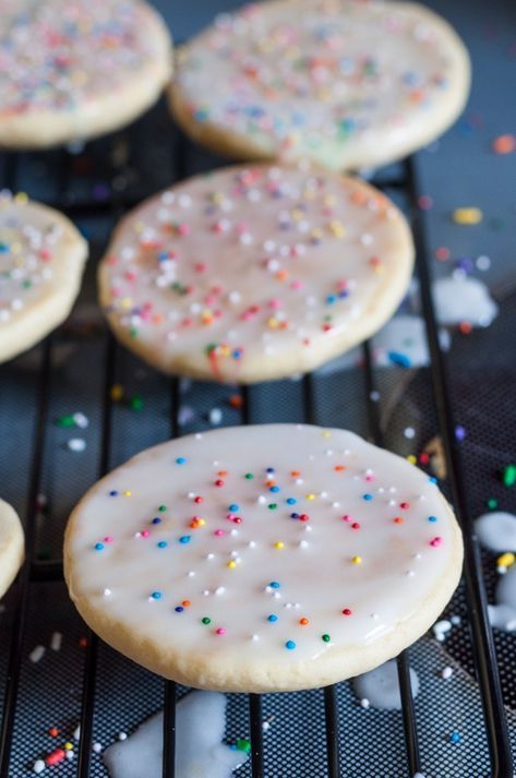 iced sugar cookies with sprinkles are cooling on a rack in the kitchen