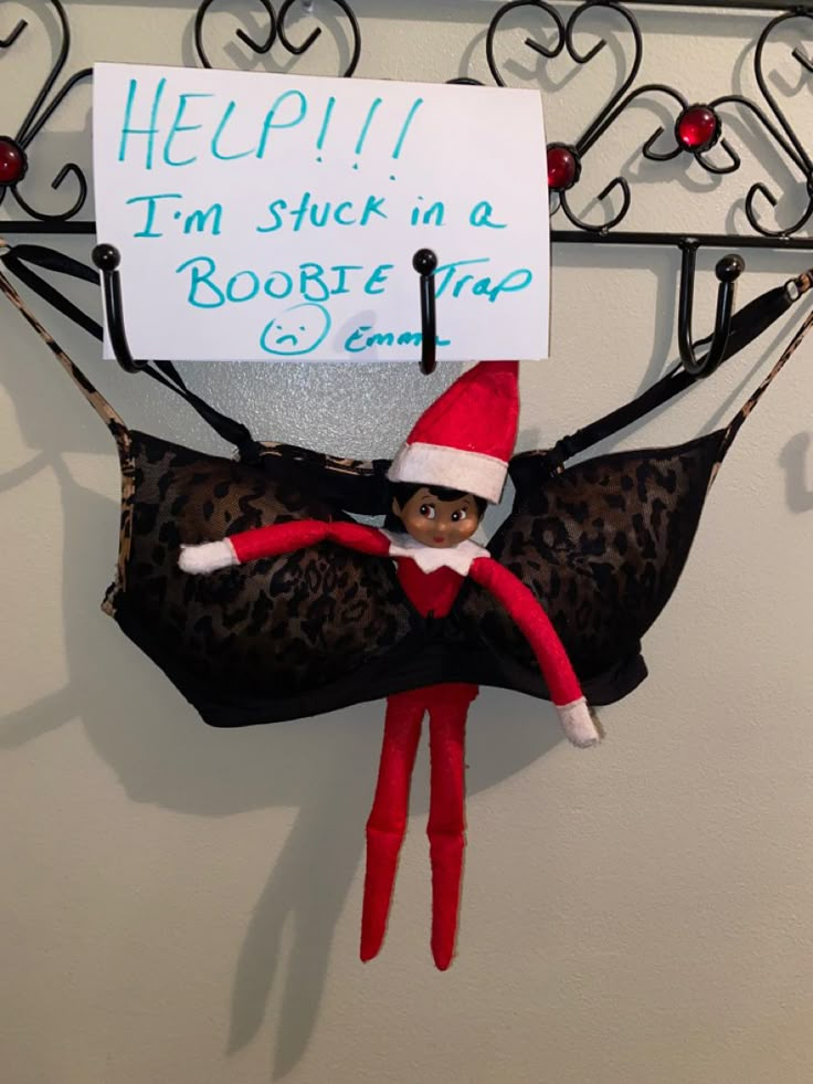 an elf is hanging on the wall next to a sign that says help i'm stuck in a boote trap