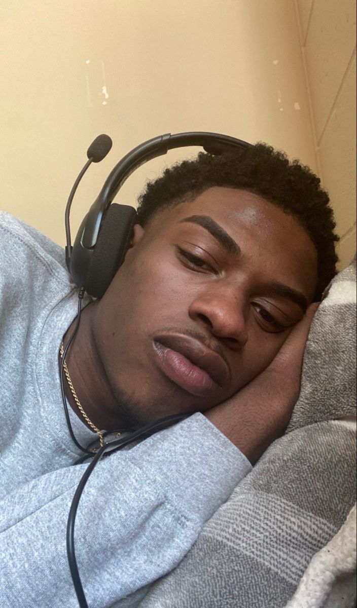 a man laying in bed with headphones on his ears