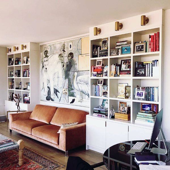 a living room filled with furniture and bookshelves next to a painting on the wall