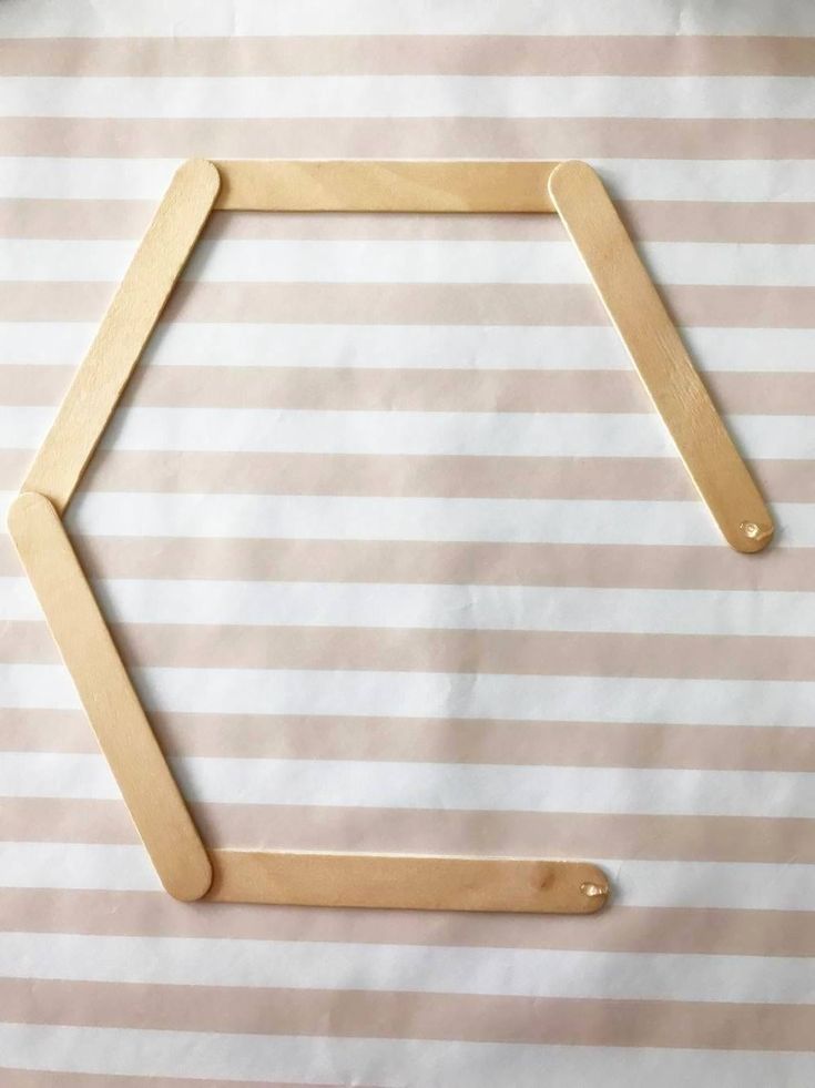 a piece of wood sitting on top of a white and pink striped paper with a hexagonal frame