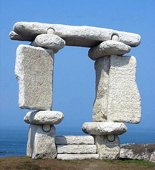 a large stone structure sitting on top of a grass covered field next to the ocean