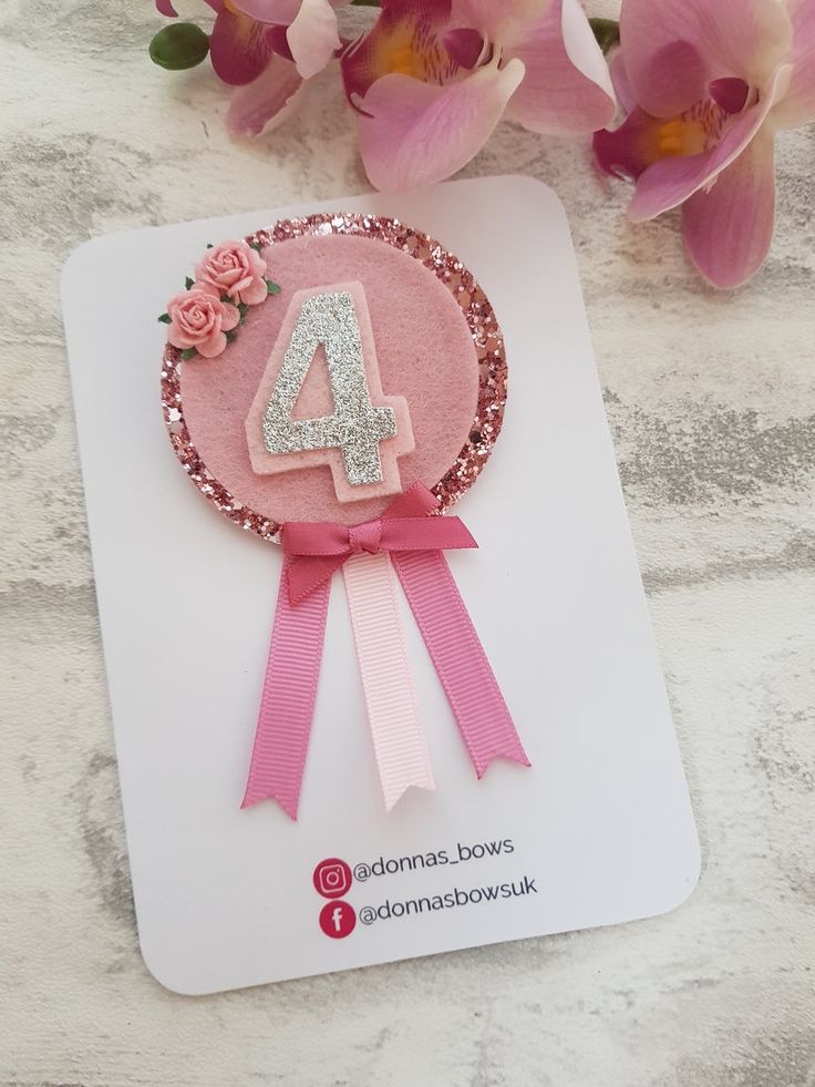 a pink ribbon with the number four on it and some flowers in front of it