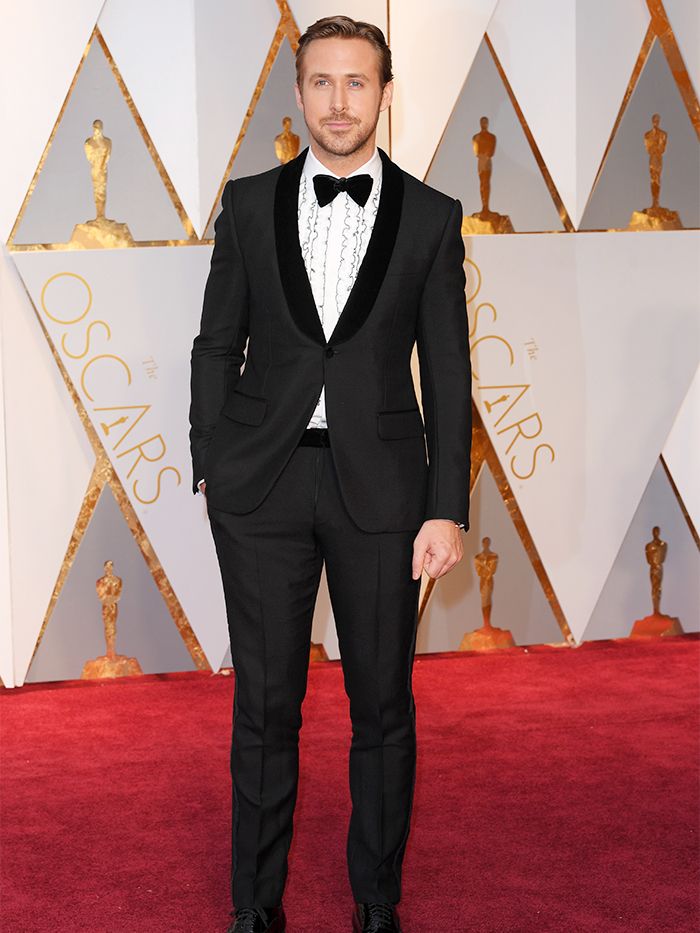 a man in a tuxedo standing on a red carpet