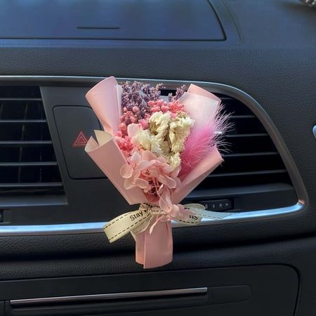 a bouquet of flowers sitting on the dashboard of a car in front of an air vent