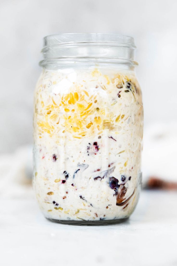 a glass jar filled with food sitting on top of a white countertop next to a wooden spoon