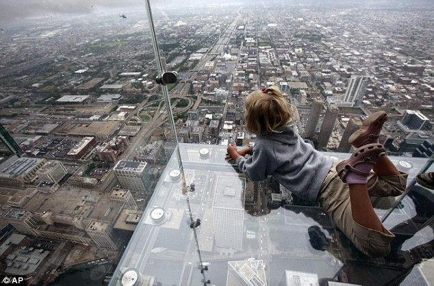 a person sitting on top of a glass floor in front of a cityscape