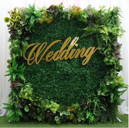 the wedding sign is surrounded by greenery and gold lettering on it's wall