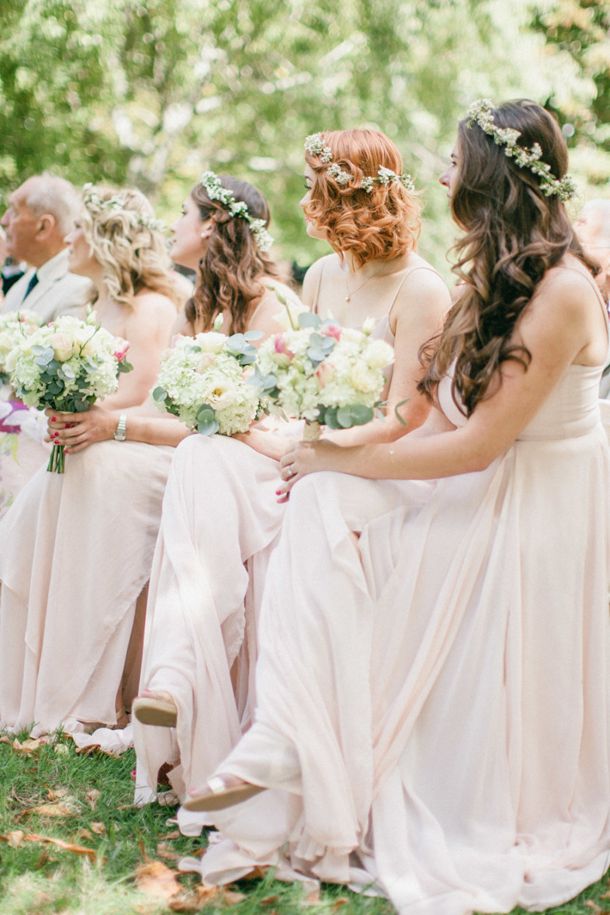 a group of bridesmaids sitting next to each other with bouquets in their hands