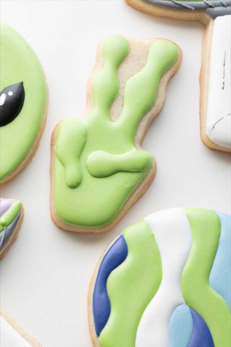 decorated cookies with green and blue icing on a white surface