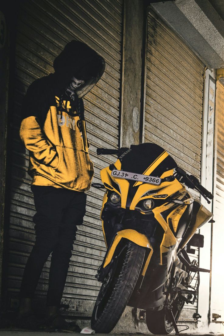 a man standing next to a yellow and black motorcycle